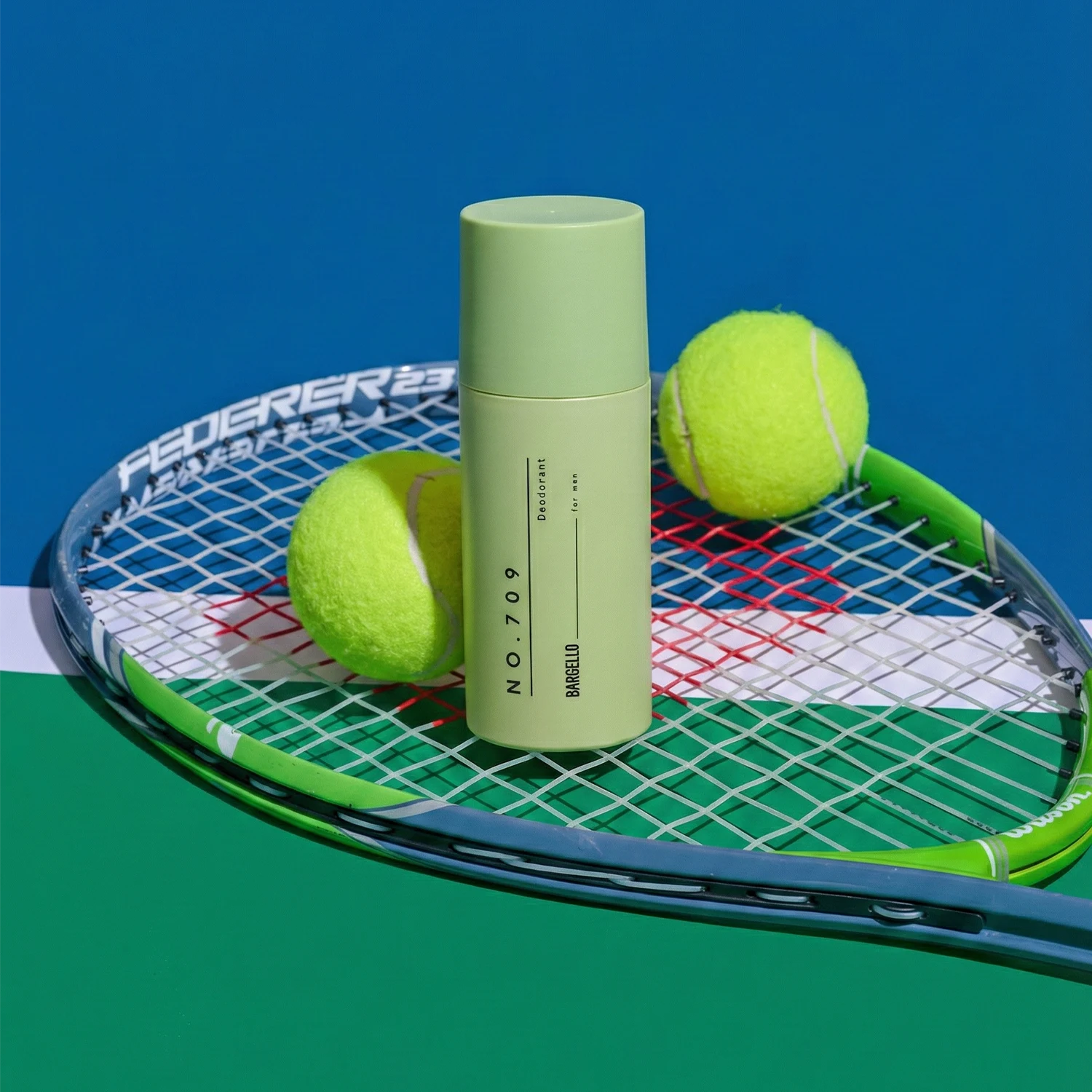 Déodorant 709 pour homme de Bargello inspiré de Stronger with You, posé sur une raquette de tennis avec des balles de tennis dans une ambiance sportive et énergique.